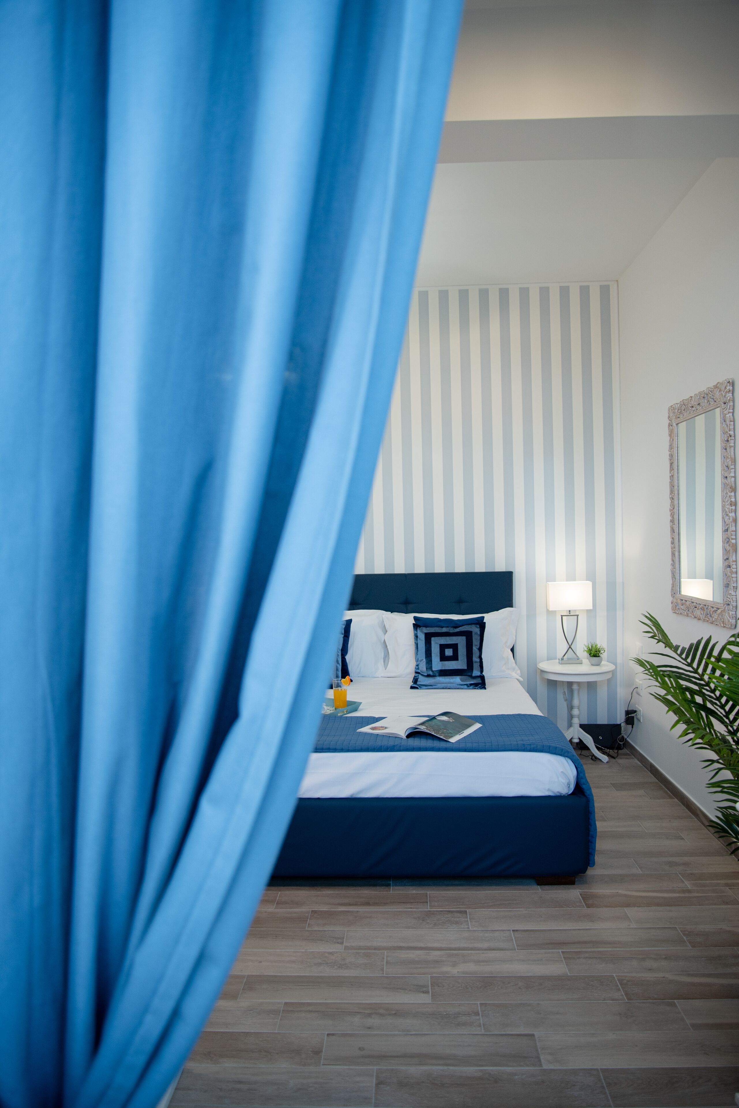 A bedroom with a bed, a bedside table, a lamp, and a mirror.