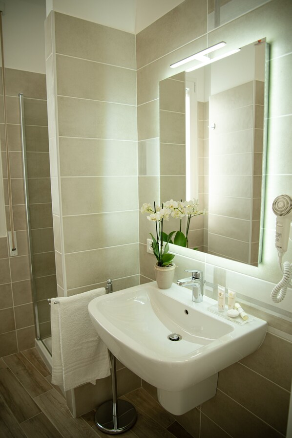 Un baño moderno con lavamanos, espejo y secador de pelo.