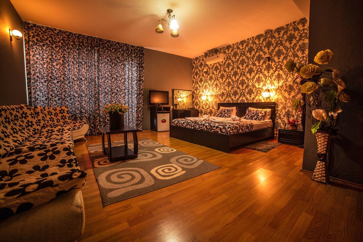 Un dormitorio con cama, sofá, televisor y un jarrón decorativo.