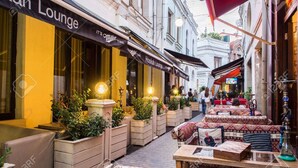 Una calle estrecha con terrazas y un edificio con un letrero que dice "Miller Lounge".