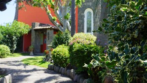 A pathway leading to a building with a red facade and a stone archway. - Villa Stefania (Barano d'Ischia)