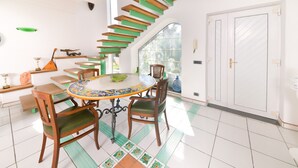 A dining area with a round table, chairs, and a staircase with green steps. - Villa Stefania (Barano d'Ischia)