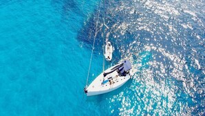 A white sailboat anchored in clear blue water. - Delfina (Lampedusa)