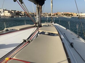 A view from a sailboat's deck with a marina and buildings in the background. - Delfina (Lampedusa)