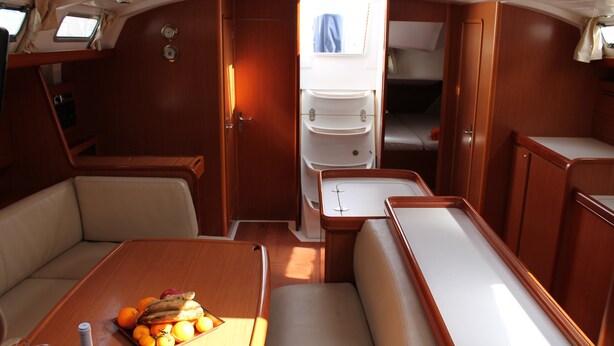 A compact boat interior with a dining area, seating, and a small kitchenette. - Delfina (Lampedusa)