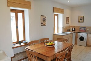 A compact kitchen with a wooden table, chairs, a washing machine, and a sink.