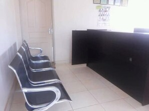 A reception area with a black reception desk and three black chairs with chrome accents. - Minachi Exclusive Lodge (Lusaka)