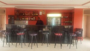 Un espace bar avec un comptoir, des tabourets et des étagères remplies de bouteilles.