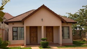 Une maison à deux étages, dotée d’une façade symétrique, d’une entrée centrale avec une double porte et d’un petit jardin à l’avant.