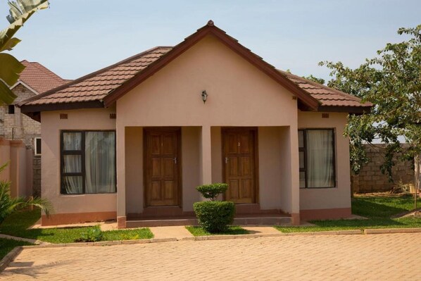 A two-story house with a symmetrical facade, a central entrance with double doors, and a small front garden. - Minachi Exclusive Lodge (Lusaka)