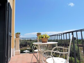 A balcony with a white metal table and chairs, potted plants, and a view of the landscape. - Villa Sciare Modò - view Etna and sea view near Catania (Acireale)