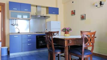 Een koelkast, een oven, kookgerei, borden en bestek, eettafels