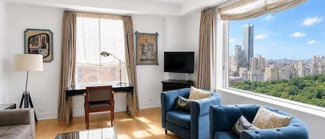 Una sala de estar moderna con vista a la ciudad, un escritorio con una computadora y un televisor de pantalla plana.