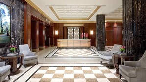 A lobby with a checkered floor, marble columns, and a reception desk.
