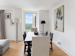 Ein stilvoller Essbereich mit einem großen Fenster, einem Esstisch, Stühlen und einer Stehlampe.
