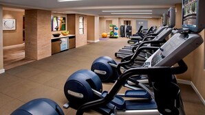 A modern gym with multiple treadmills, stationary bikes, and exercise balls.