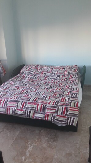 A room with a bed covered by a striped blanket, a chair, and a tiled floor. - Villa Hmoud (Amman)