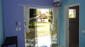 A room with a sliding glass door leading to a patio, a television mounted on the wall, and a small table with a chair.