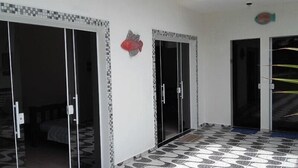 A room with a tiled floor, a bed, and a door with a fish decoration.