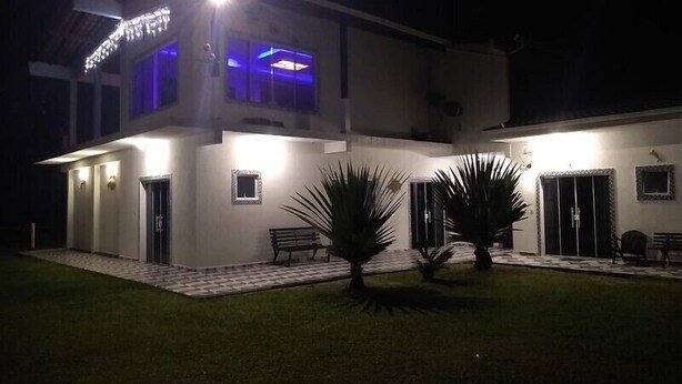 A modern two-story house with a well-lit entrance and a covered patio area.