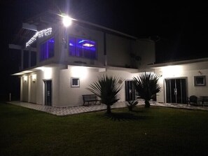 A modern two-story house with a well-lit entrance and a covered patio area. - Pousada Camping e Pesca Bom Abrigo (Ilha Comprida)