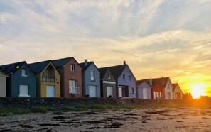 A row of colorful houses with a sunset in the background. - Waterfront villa direct access to the beach (Saint-Marcouf)