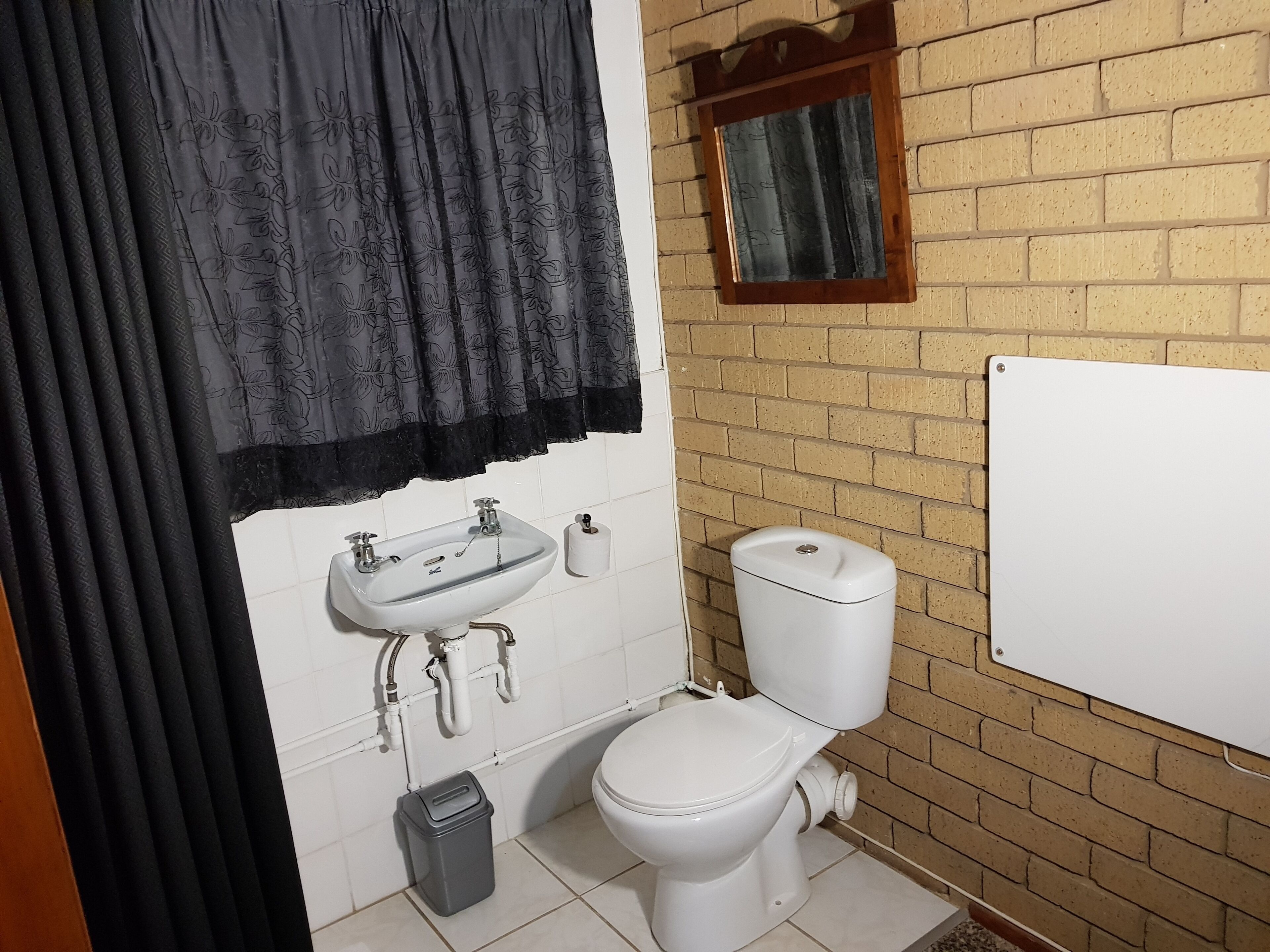 A bathroom with a sink, toilet, and a small window.