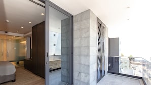 A modern bedroom with a glass door leading to a balcony, a wooden floor, and a view of the cityscape. - Bradway Apartments (Cape Town)