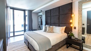 A modern bedroom with a large bed, a dark headboard, and a bedside table with a lamp. - Bradway Apartments (Cape Town)