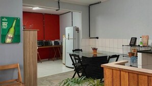 A compact kitchen with a dining area, a refrigerator, a microwave, and a potted plant.