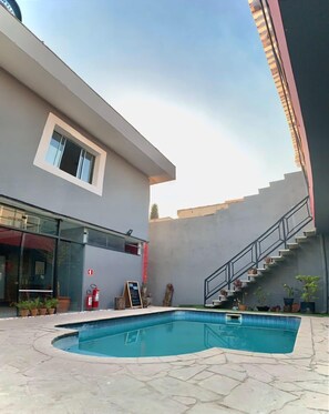 A modern building with a swimming pool, a staircase, and a fire extinguisher. - Kaleidoscópio Hostel (São Paulo)