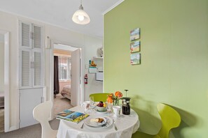En matplats med ett bord dukat för två personer, en vit stol, en grön stol och en bokhylla i bakgrunden.