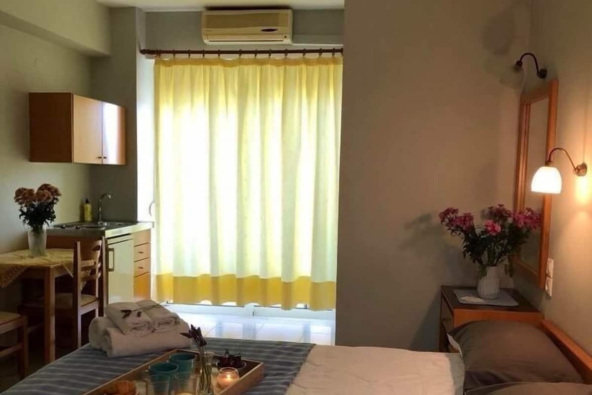 A hotel room with a bed, bedside table, lamp, and a window with curtains.