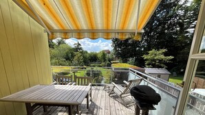 A wooden deck with a table and chairs, a grill, and a view of a garden and house in the background. - Large Apartment with Sauna in central Buxtehude.
NO RENTAL TO FITTERS. (Buxtehude)