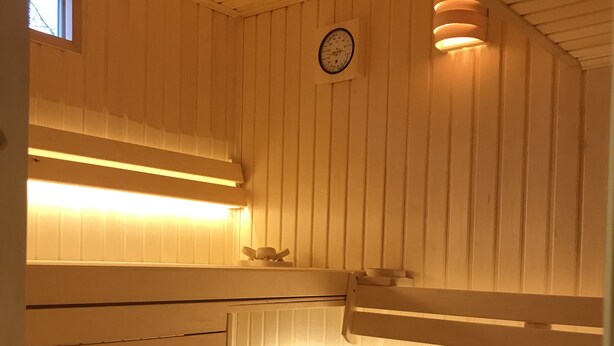 A sauna with wooden benches, a wall-mounted clock, and overhead lighting. - Large Apartment with Sauna in central Buxtehude.
NO RENTAL TO FITTERS. (Buxtehude)