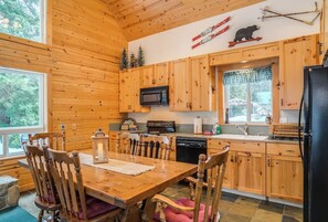 Une cuisine aménagée dans le style d’un chalet en bois, avec une table à manger, des chaises, un four à micro-ondes et un réfrigérateur.