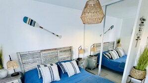 Une chambre moderne avec un grand lit, un miroir et un luminaire suspendu.