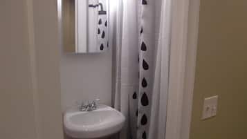 Une salle de bain avec un lavabo blanc, un miroir au-dessus et un rideau de douche à motifs à pois.
