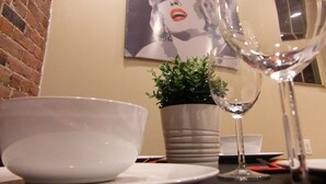 A dining table with a white bowl, a glass of white wine, and a potted plant. - Studios Midtown Manhattan (New York)