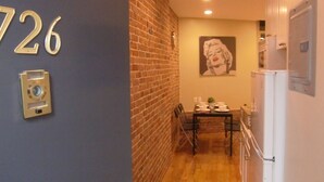 A narrow hallway with a brick wall, a number '726' sign, a table set for dining, and a refrigerator. - Studios Midtown Manhattan (New York)