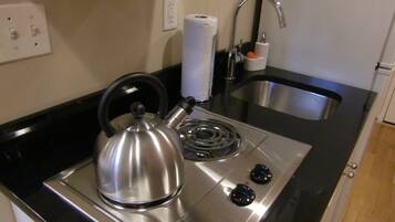 A kitchen with a kettle, a sink, and a stove.