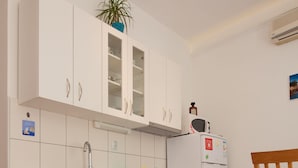 A compact kitchen with white cabinets, a microwave, and a small refrigerator. - Apartments Val (Split)