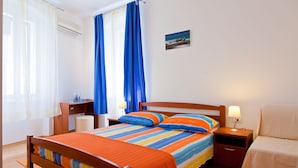 A neatly arranged bedroom with a wooden bed, a bedside table, a nightstand, and a small desk. - Apartments Val (Split)