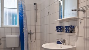 A bathroom with a shower, toilet, sink, and a window. - Apartments Val (Split)