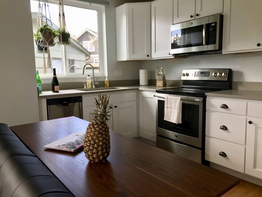 A modern kitchen with white cabinets, a stainless steel oven, and a microwave.