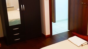 A bedroom with a bed, a wardrobe, and a door leading to a balcony.