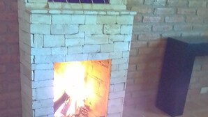 A fireplace with a fire, tiled floor, and a brick wall. - 15  cabins in and Exclusive and private area inside the  Valladolid Acuatic Park (Aguascalientes)