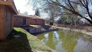 A brick building with a tiled roof, a small pond, and a tree in the background. - 15  cabins in and Exclusive and private area inside the  Valladolid Acuatic Park (Aguascalientes)