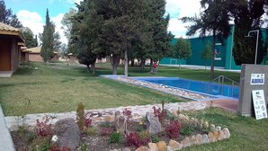 A swimming pool surrounded by a stone border, trees, and a grassy area with a sign reading "ALBERCA". - 15  cabins in and Exclusive and private area inside the  Valladolid Acuatic Park (Aguascalientes)
