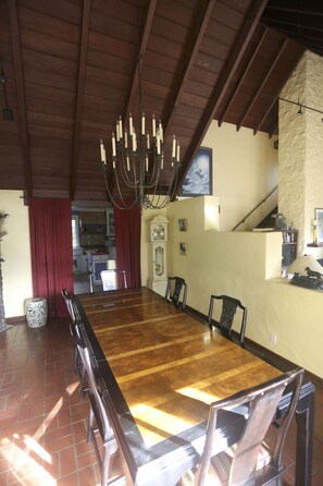 Zona pranzo con un lungo tavolo in legno, sedie e un lampadario.